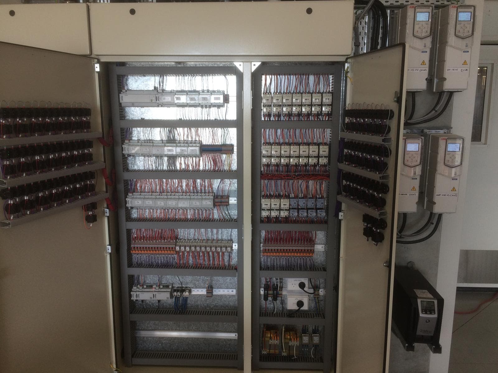 Large open control cabinet with internal wiring and external HVAC drives