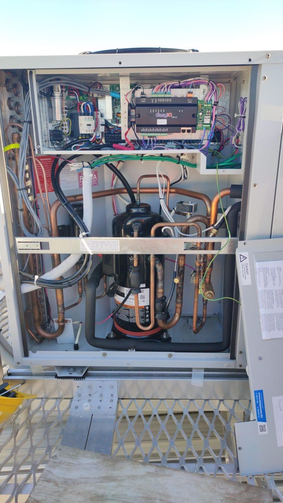 Open packaged HVAC unit showing controller wiring and copper pipework