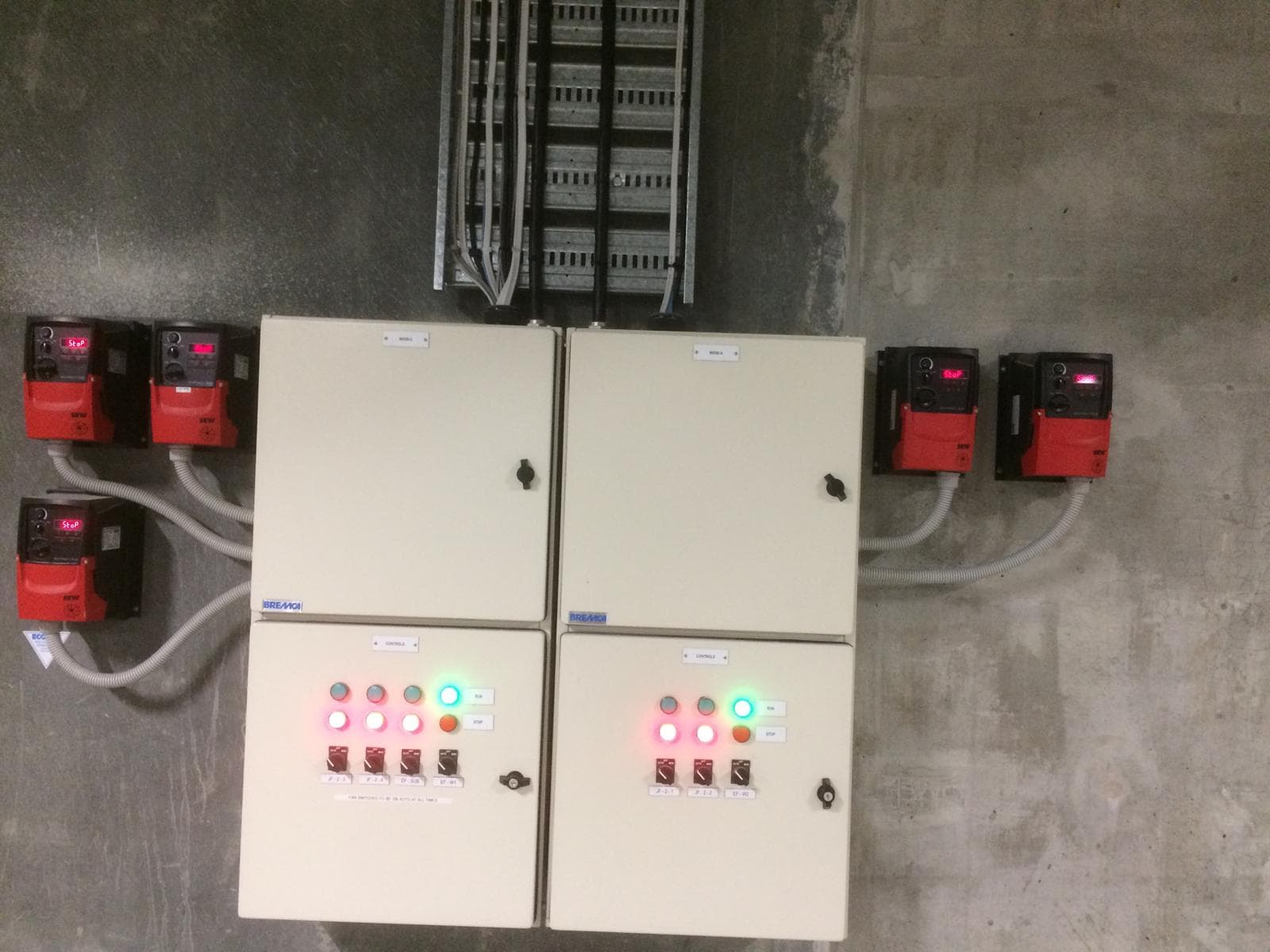 Pump control panels and red drive controllers installed on a concrete wall
